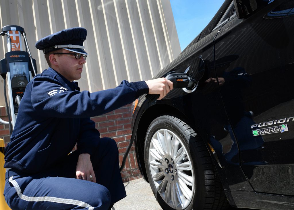 An airman plugs in an electric vehicle