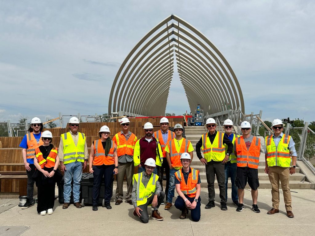 workers in hard-hats posing in front of structure