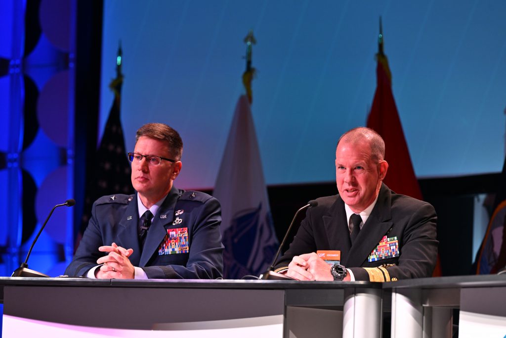 Two military officers speak on a stage